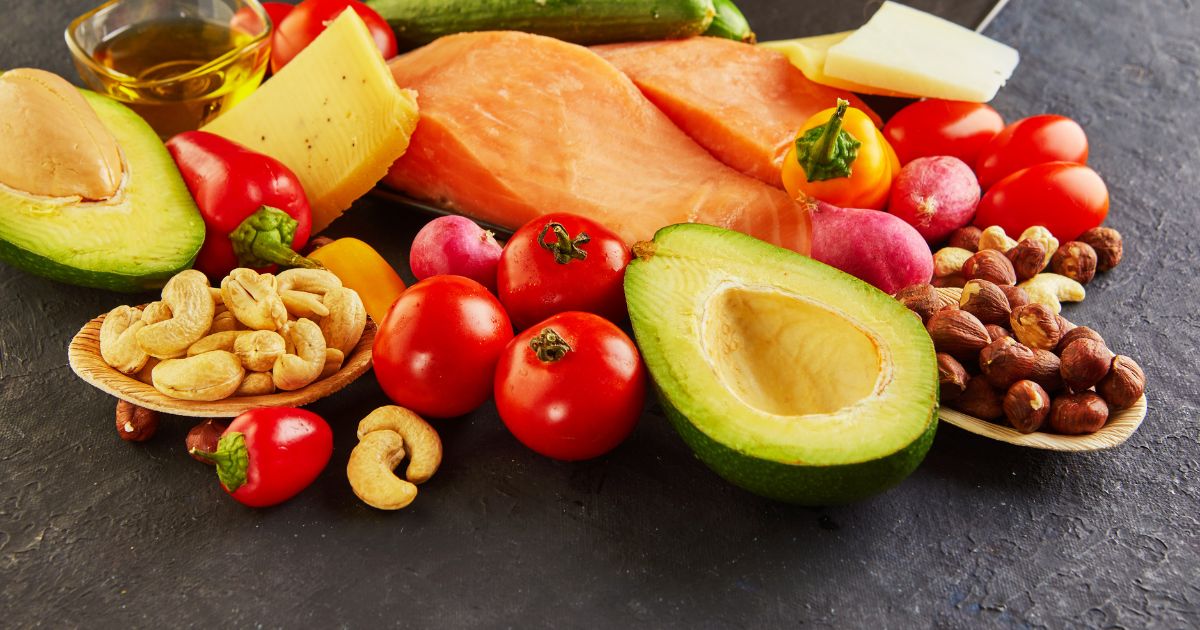 keto diéta — losos, avokádo, syr, paprika a orechy na čiernom podklade
